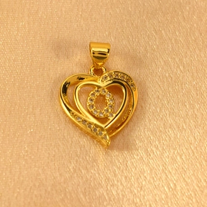 Detailed view of a gold-plated double heart pendant with white crystals on silk background