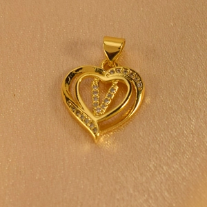 Macro view of gold heart pendant featuring sparkling zircon micro-pave letter V