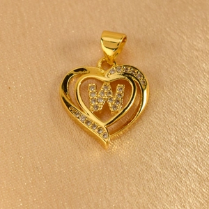 Macro detail of gold heart pendant with crystal encrusted letter W on silk background