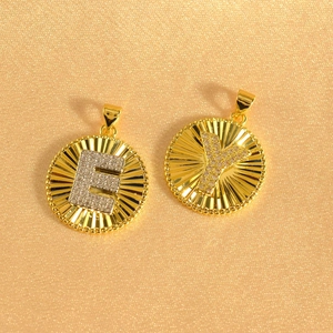 Detail view of round gold plated sunburst pendants with micro-pave CZ E and Y letters