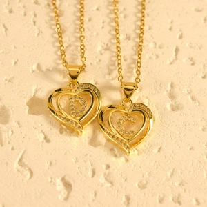 Gold plated heart pendant necklace with crystal letter D and C on stone background
