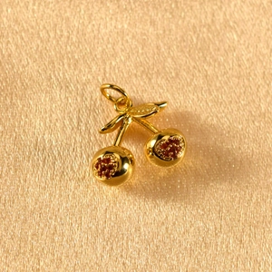 Macro shot of sparkling cherry pendant with red crystals and golden leaves details