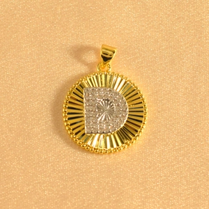 Detailed close-up of a gold-plated circular sunburst pendant featuring an iced-out letter D