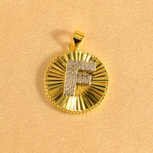 Macro shot of gold-plated sunburst pendant featuring zircon-encrusted letter F detail