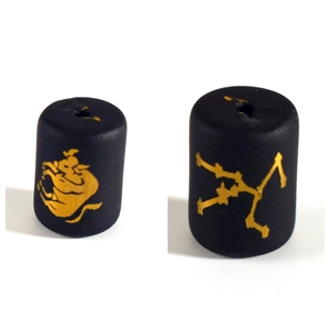 Macro shot of matte black zodiac glass beads with gold painted Taurus and star patterns