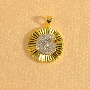 Macro detail of gold plated sunburst pendant featuring an iced out crystal letter G center