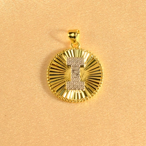 Macro shot of gold sunburst pendant featuring an iced-out letter I with micro-pavé crystals