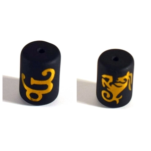 Macro detail of black cylindrical zodiac charms with golden Capricorn constellation symbol