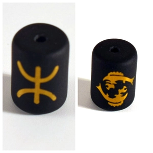 Detailed macro view of black matte cylinder beads featuring golden zodiac and cultural symbols