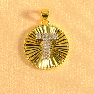 Detail of gold sunburst pendant with crystal-encrusted letter T on champagne fabric