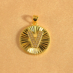 Detailed view of gold sunburst pendant with crystal letter V and beaded edge