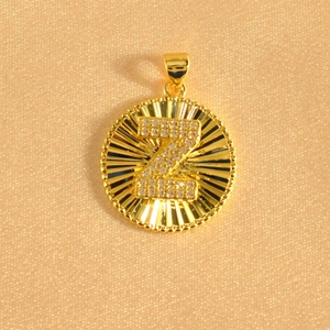 Macro detail of gold-plated sunburst pendant with sparkling letter Z crystal inlay