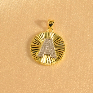Detailed macro view of gold sunburst pendant with letter A and micro-paved zircons