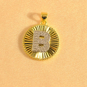 Detail of gold sunburst pendant with crystal-encrusted silver letter B center