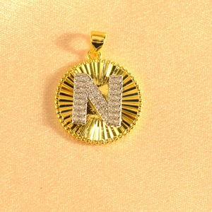 Macro shot of gold sunburst pendant with crystal-encrusted silver letter N detail