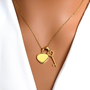 Elegant gold stainless steel necklace featuring a heart and key double pendant on model