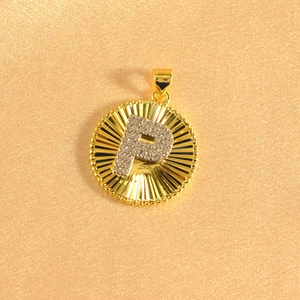 Detailed close-up of a gold-plated sunburst pendant with sparkling zircon letter P
