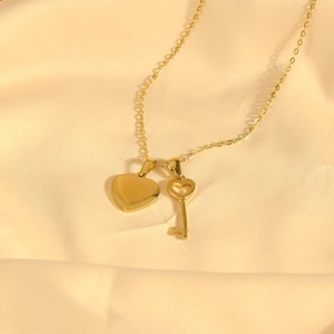 Elegant gold heart and key pendant necklace on premium silk fabric background