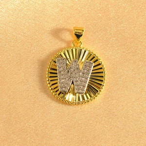 Detail of gold-plated sunburst pendant featuring a crystal-encrusted letter W in the center