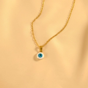Detalle del collar ojo turco dorado con colgante de esmalte azul sobre seda amarilla