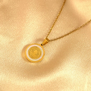 Detailaufnahme des goldenen St. Benedikt Medaillon-Anhängers mit Perlmutt-Inlay auf Seide