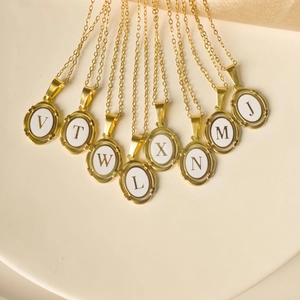 Close-up of golden oval letter pendants with white enamel on a stainless steel chain