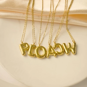 Makro-Detail goldener Ballon-Buchstabenanhänger mit glänzendem Finish auf feinen Ketten