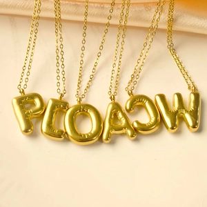 Minimalistische goldene 3D-Buchstabenhalsketten auf beigem Hintergrund