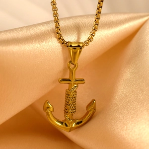 Polished gold anchor pendant necklace with rope detail on champagne silk background