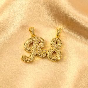 Nahaufnahme glitzernder Strass besetzter Buchstabe R und Zahl 8 Anhänger auf goldener Seide.