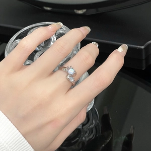 Macro shot of silver liquid metal ring with moonstone worn by a hand holding glass