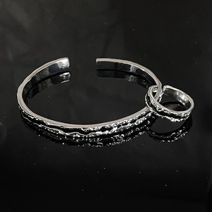 Close-up of irregular silver cuff bracelet with unique hammered lava texture finish