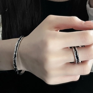 Irregular textured silver bangle and ring set with hammered finish on black background