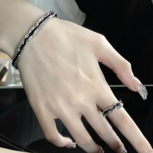 Macro detail of irregular textured silver cuff bracelet and ring set with black enamel inlay