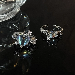 Irregular silver moonstone heart ring with pavé crystals on a reflective black background