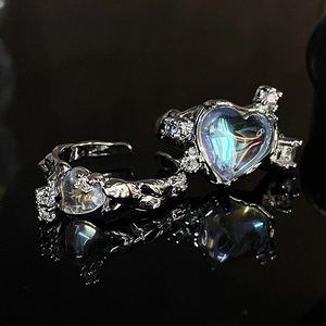 Detail of silver heart moonstone ring set with irregular ice textures on black mirror