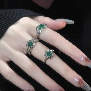 Detalle de anillos de metal plateado irregular con piedras de ágata verde en los dedos