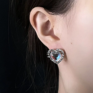 Close-up of heart-shaped moonstone stud earring with silver rope border on model's ear