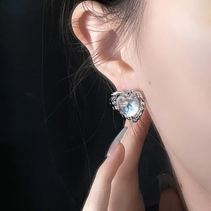 Macro close-up showing heart-shaped moonstone earrings with liquid metal silver texture