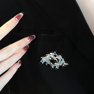 Artistic silver textured metal brooch with blue enamel on a stylish black blazer