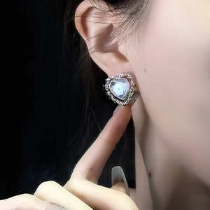 Elegant moonstone heart stud earrings with twisted silver metal border on female model