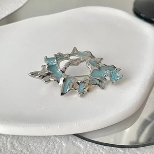 Artistic silver lava textured brooch with light blue stones and enamel inlay