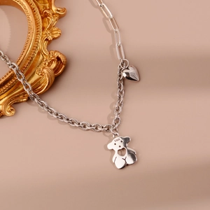 Gros plan détaillé des pendentifs ours et cœur en argent S925 avec chaîne texturée