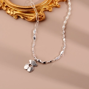 Détail du collier avec perles blanches, chaîne argentée et pendentif ours poli