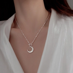 Detail of silver crescent moon necklace featuring shimmering texture and OT toggle clasp