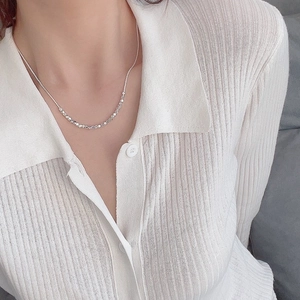 Close-up of sparkling silver crushed bead necklace worn with a white striped shirt