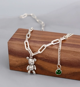 Détail du pendentif ours argenté avec gravure Peace Love et pierre verte sur chaîne