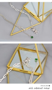 Détail du collier argenté double couche avec pendentif ours mécanique et gemme verte