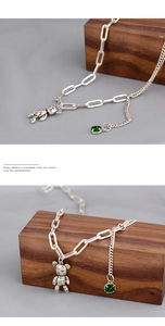 Détail du pendentif ours avec pierre verte sur un collier à chaîne mixte asymétrique