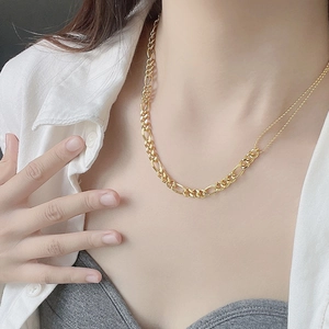 Detail einer vergoldeten Gliederkette mit Figaro-Gliedern und Perlen an einem Model